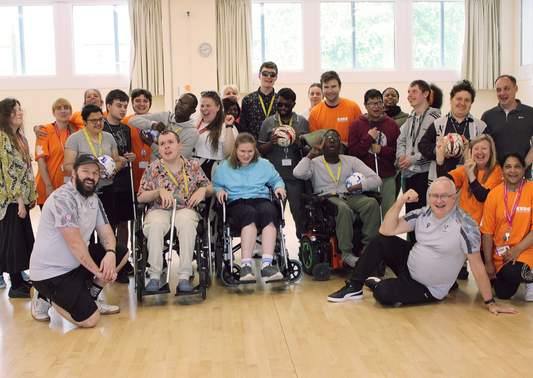 A group of Dorton College students, Palace for Life staff and Dorton College staff, some standing, some crouching and some in wheelchairs, in a sports hall where they're smiling at the camera after their football activities.