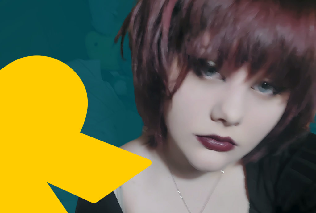 A headshot of Lauren who has burgundy-coloured hair, the same coloured lipstick, and blue eyes. She stares at the camera intently, and there is a yellow graphic of the letter R to the left of her face.
