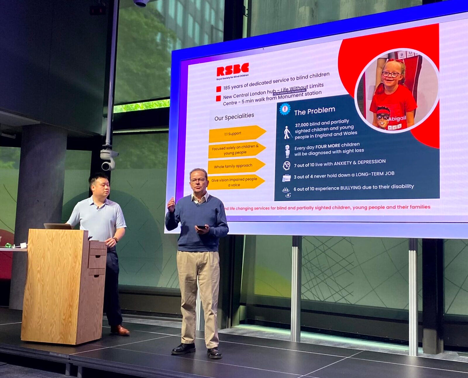 Kevin and Alex are standing in front of a big screen giving a talk about RSBC