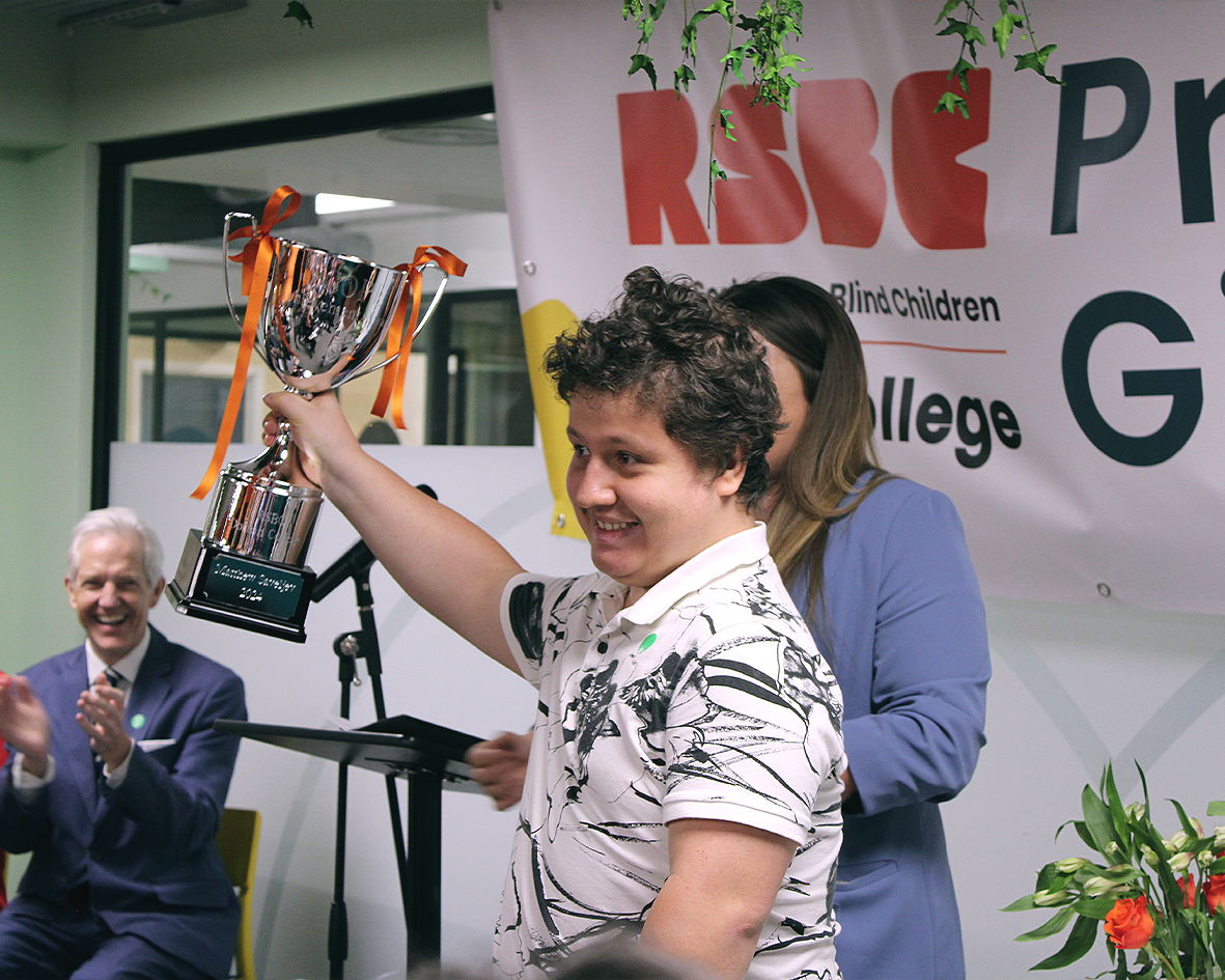 A happy student, holding up a large trophy victoriously