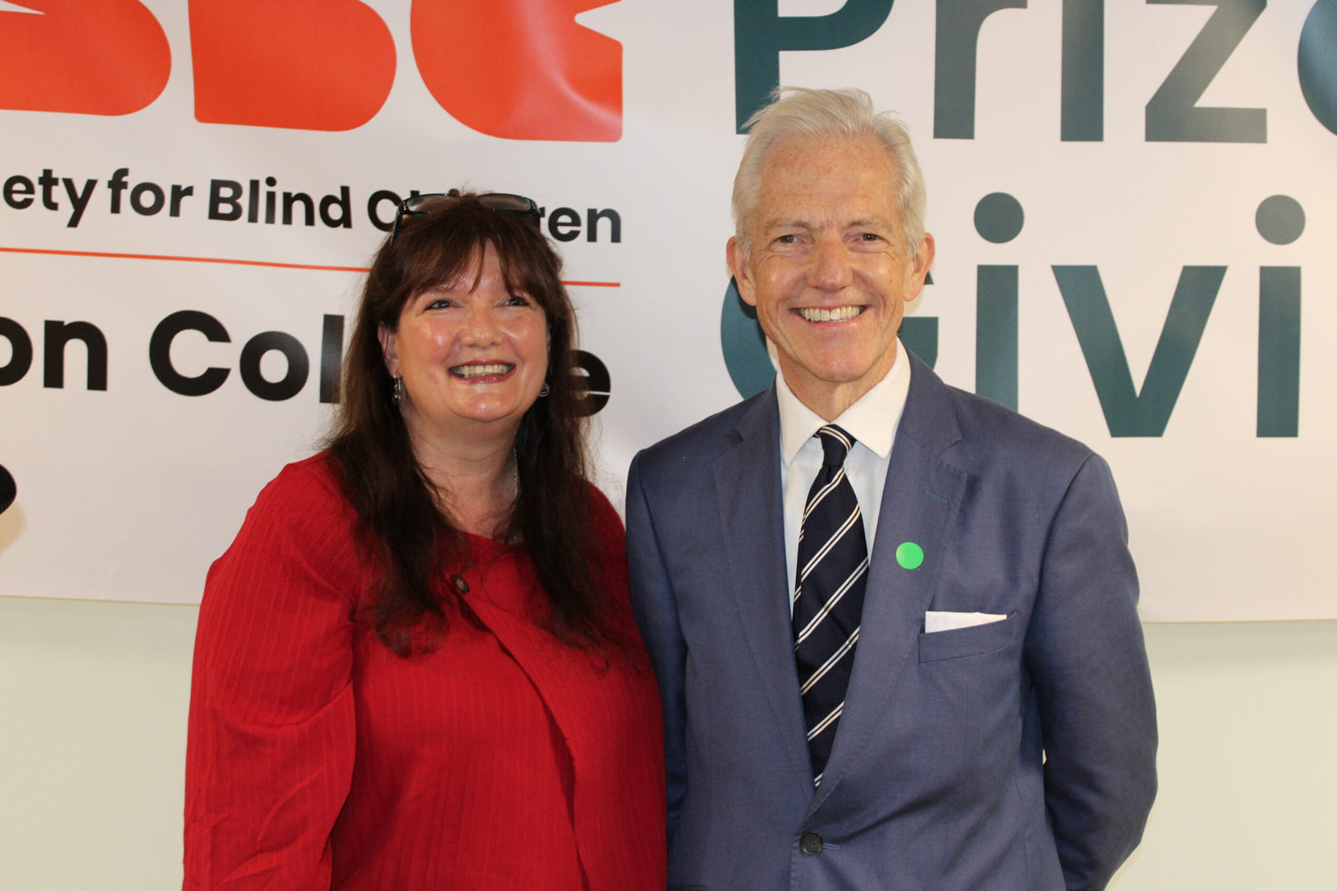 Our Chair of Trustees and CEO are standing against a branded RSBC backdrop and smiling at the camera