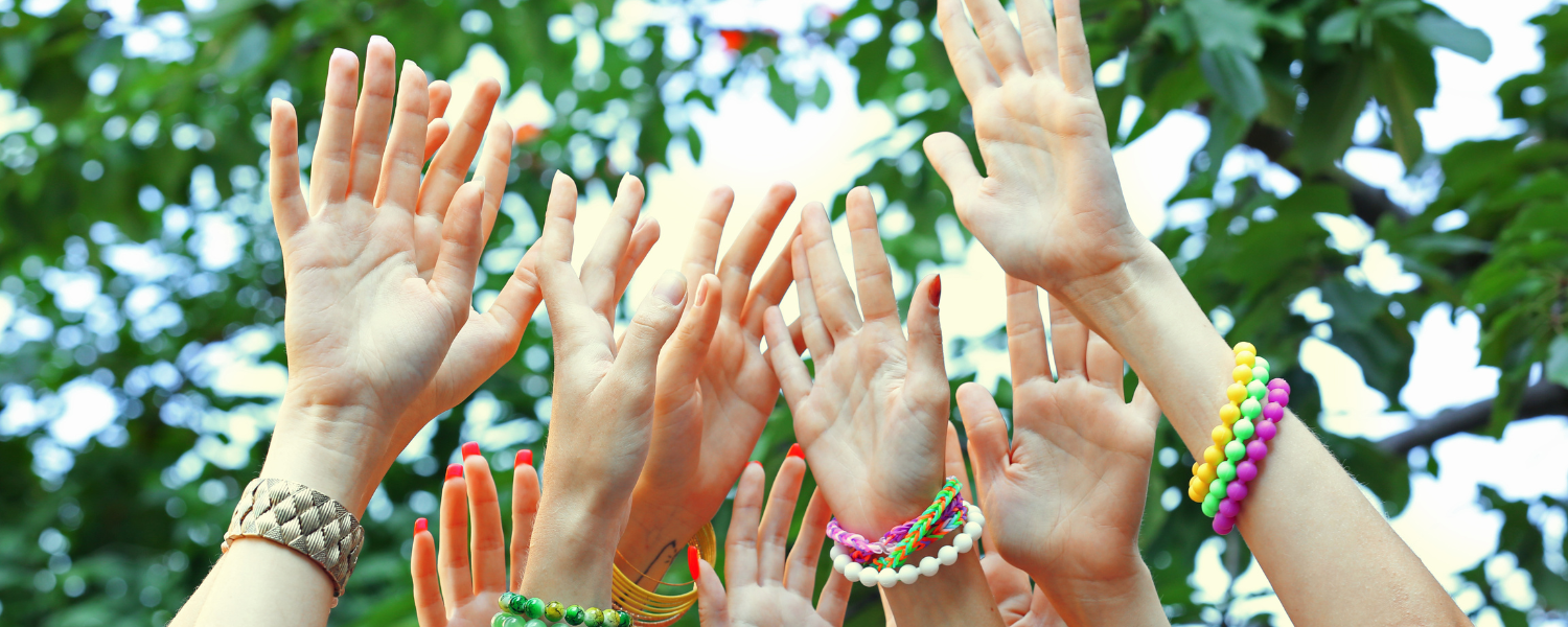 A close up shot of several pairs of hands raised in the air in celebration