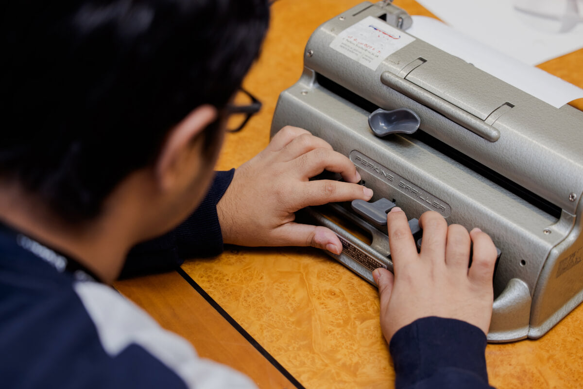 a young man using a Perkins brailler