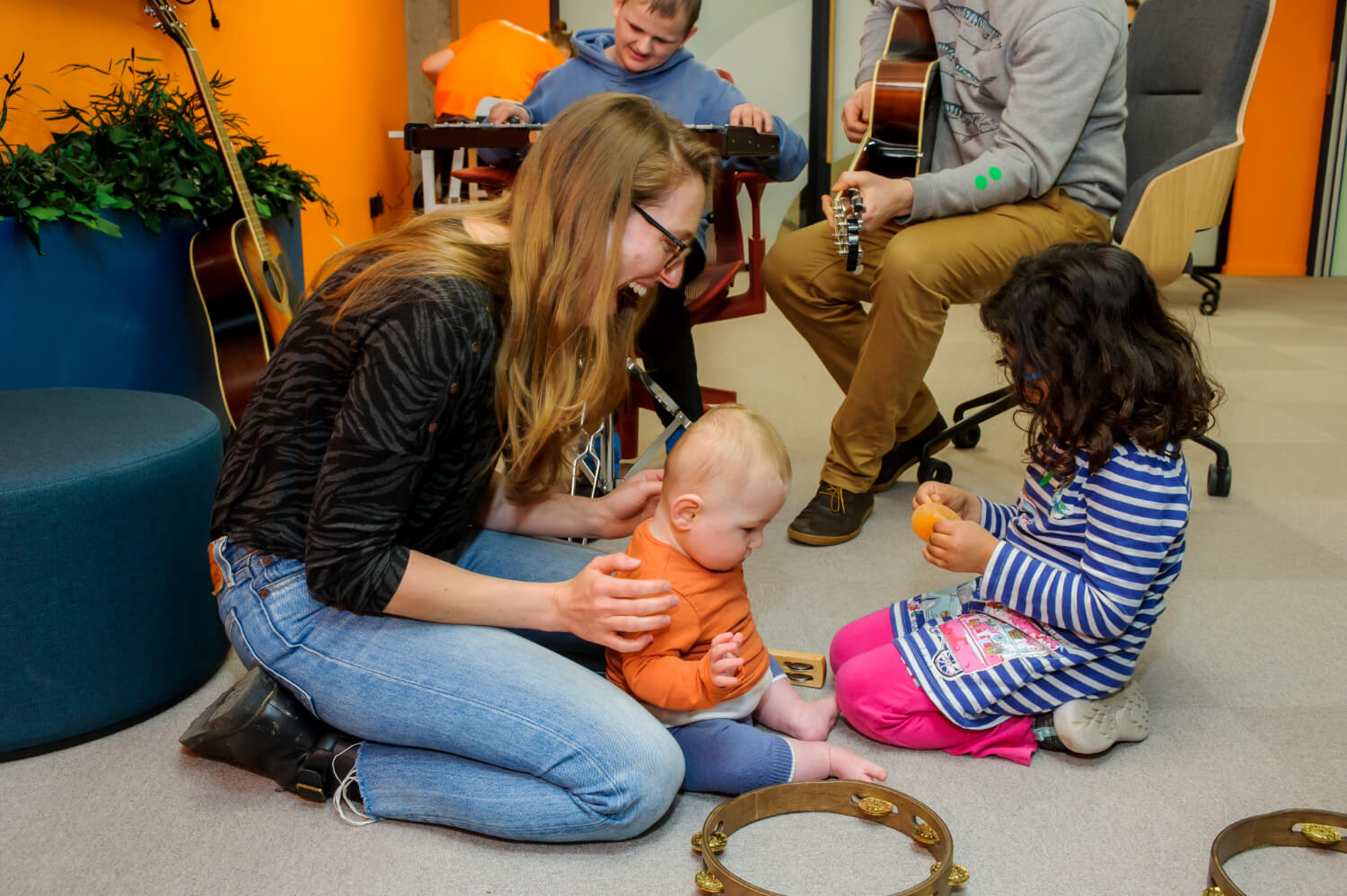 A happy group of adults, young people and children playing musical instruments in our creative suite
