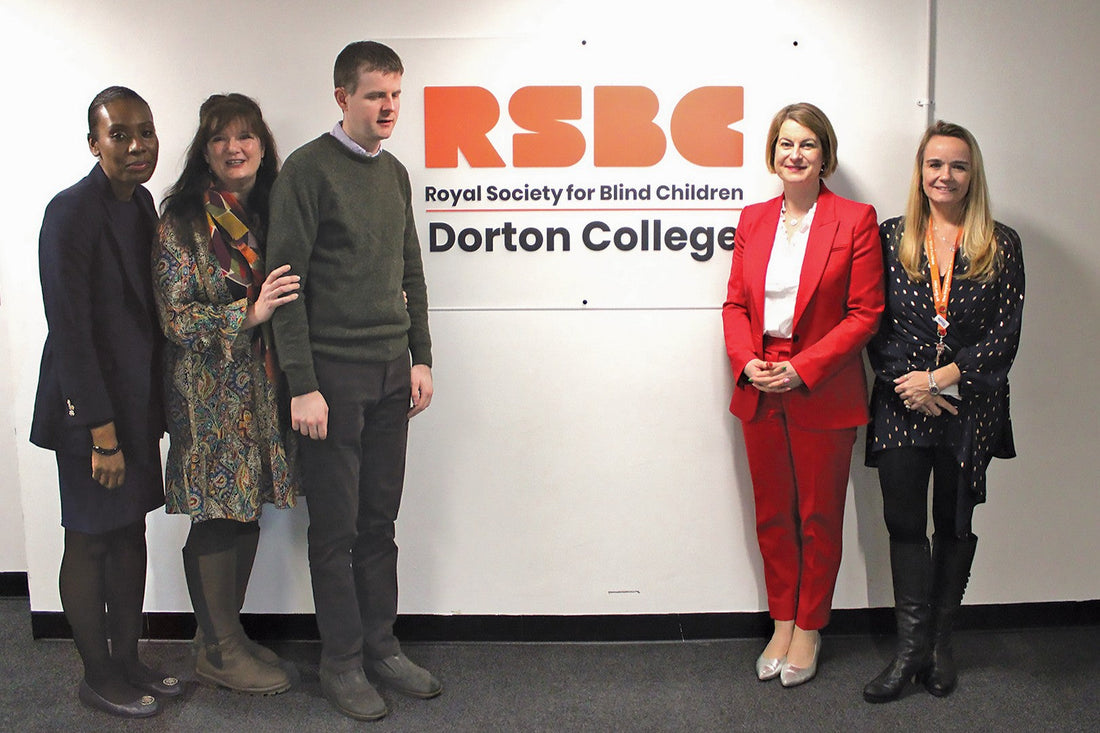 Five people stand at either side of the RSBC Dorton College sign, smiling slightly at the camera.
