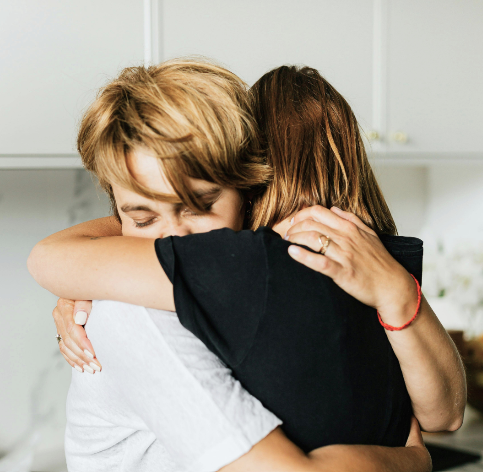 A mother and daughter hugging in the kitchen.