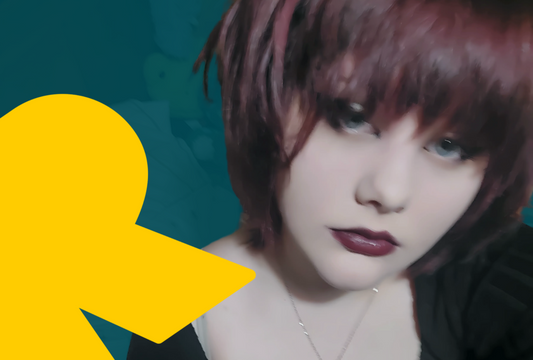 A headshot of Lauren who has burgundy-coloured hair, the same coloured lipstick, and blue eyes. She stares at the camera intently, and there is a yellow graphic of the letter R to the left of her face.