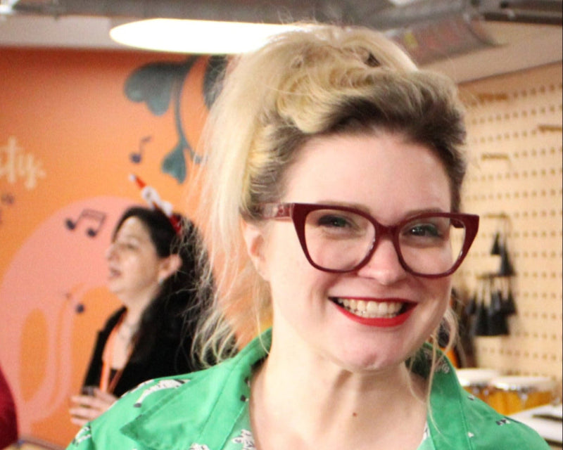 Woman wearing red glasses and a green shirt with a blurred background