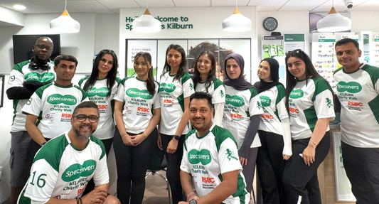 Group of 12 Specsavers Kilburn team members wearing branded green and white team shirts posing inside the Specsavers store.