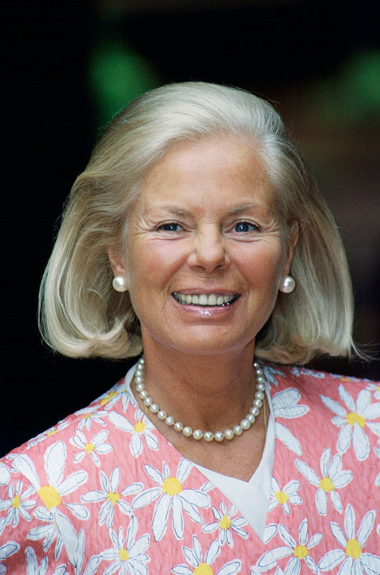 The Duchess of Kent, who has shoulder length bobbed blonde hair and is wearing pearl earrings and necklace and a pink and white flowery jacket as she smiles happily.