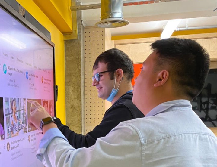 Two people using a large touch screen
