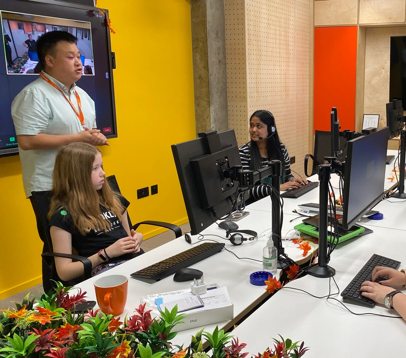 A group of young people at computers and using headphones in our learning suite with our Assistive Technology Officer