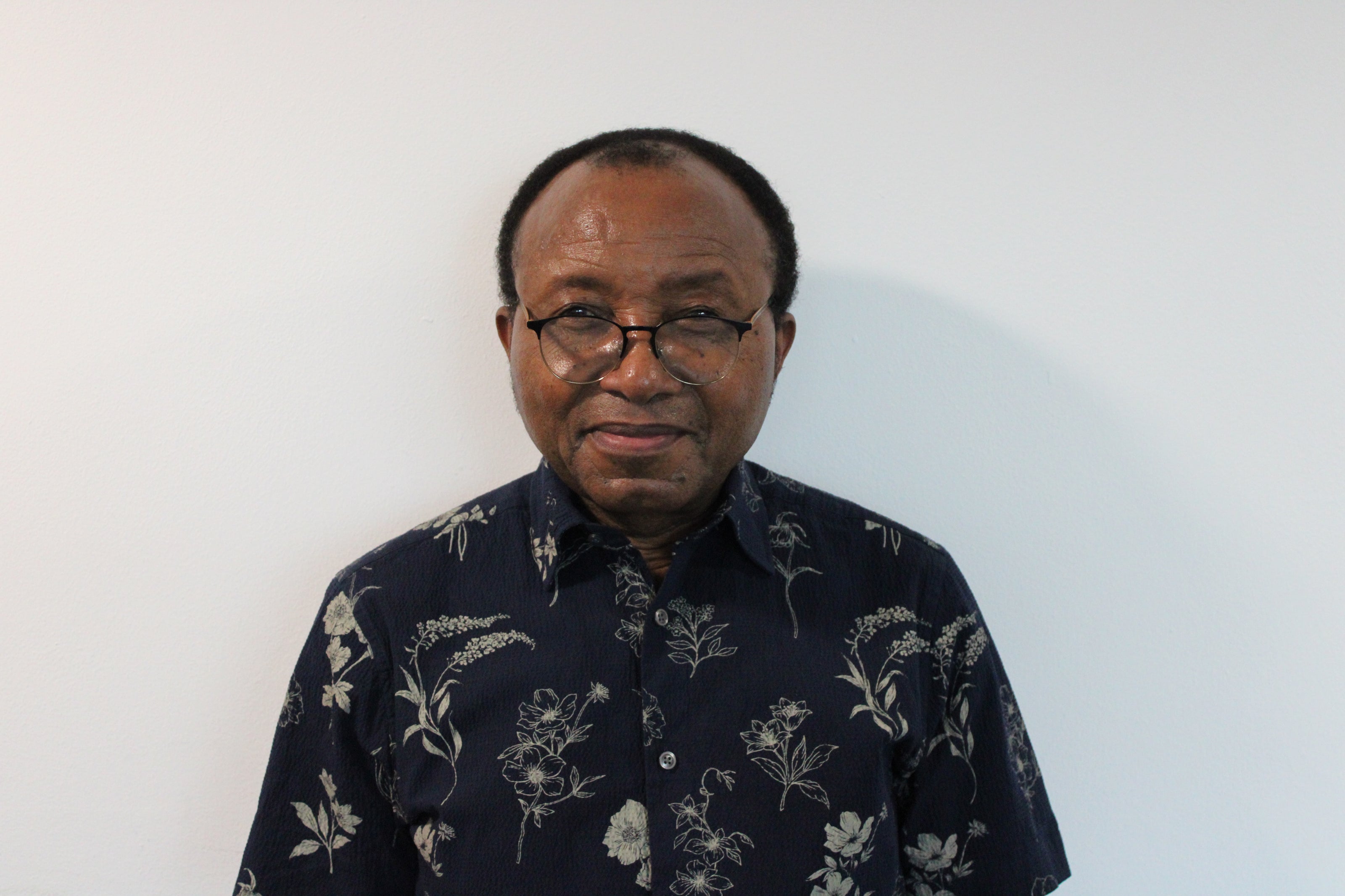 Charles, a man wearing a dark floral shirt against a white background