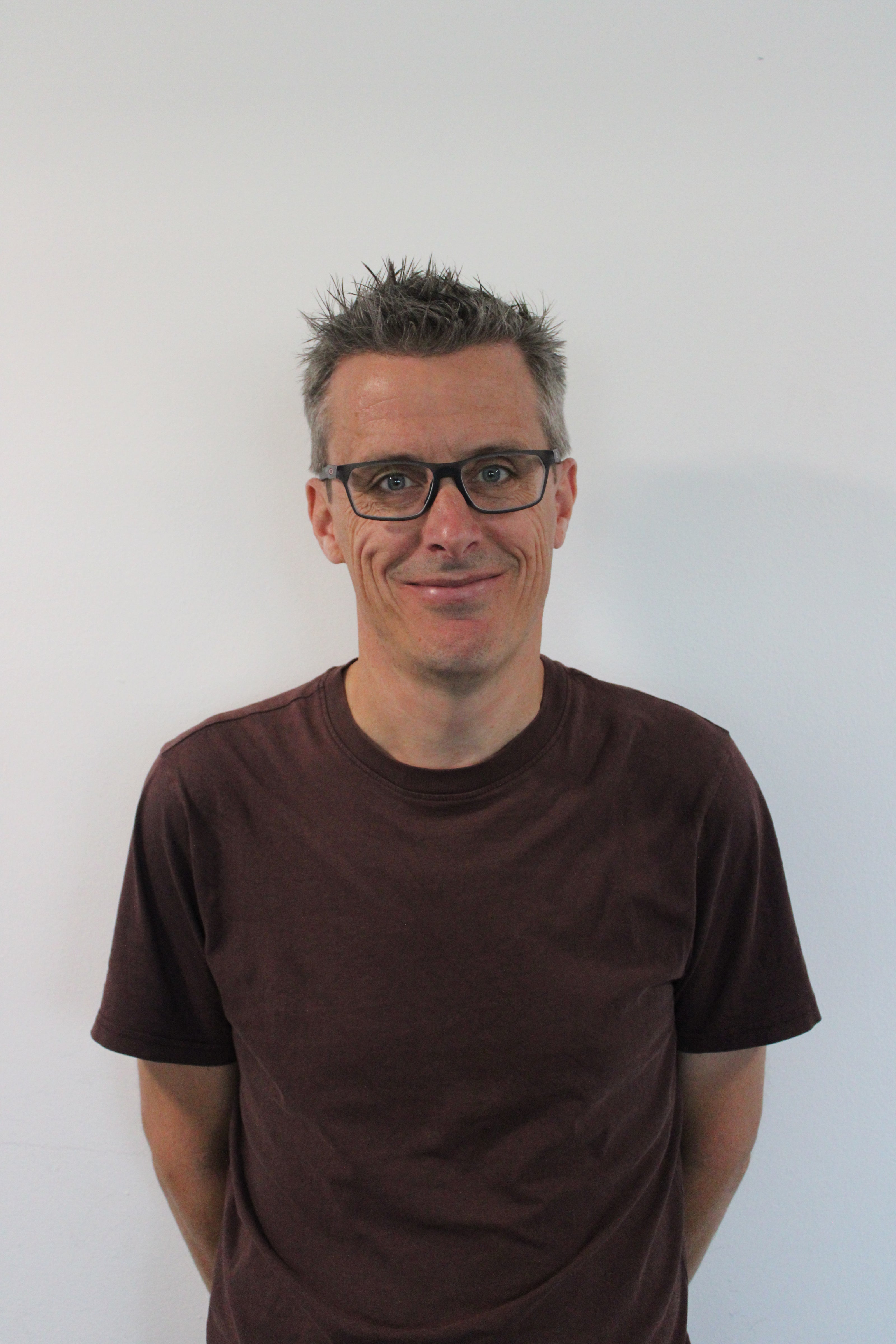 Steve, a man wearing glasses and a brown shirt against a white background