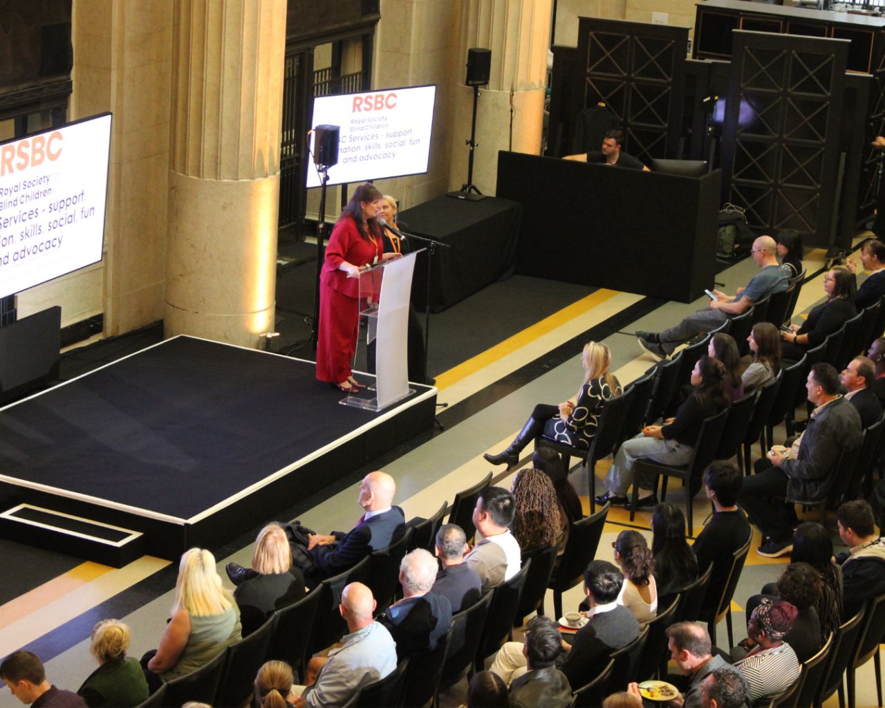 Julie Davis, CEO of RSBC on stage at a conference with audience and screens in the background
