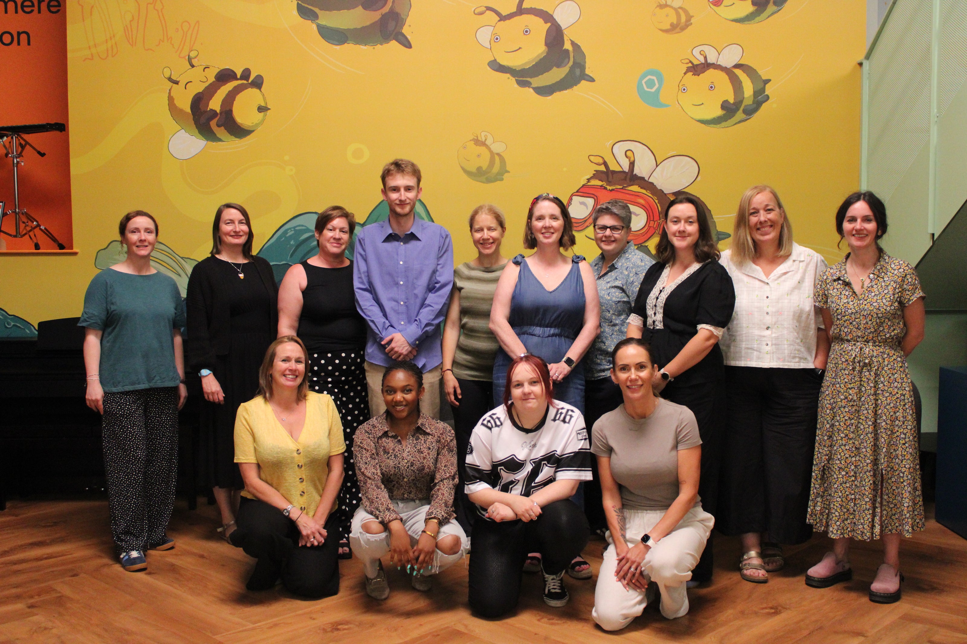 RSBC staff from the Family Support team posing for a photo in front of a colorful wall with bee illustrations.