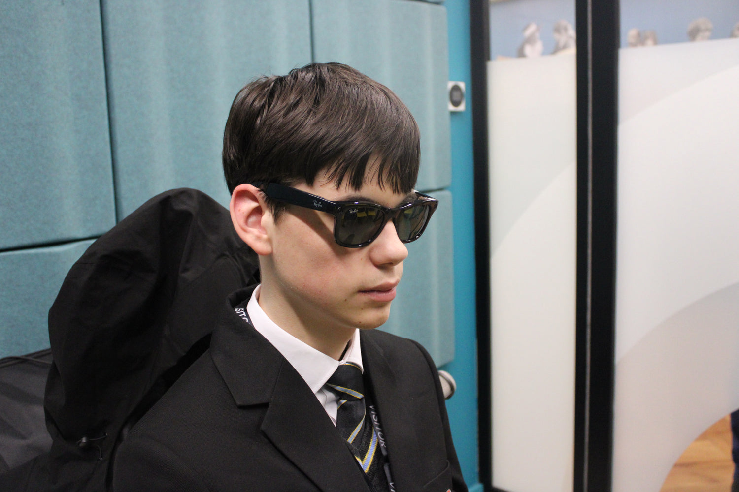 A boy wearing a black school blazer and the Ray-Ban Meta Glasses, testing them at the LWLC.