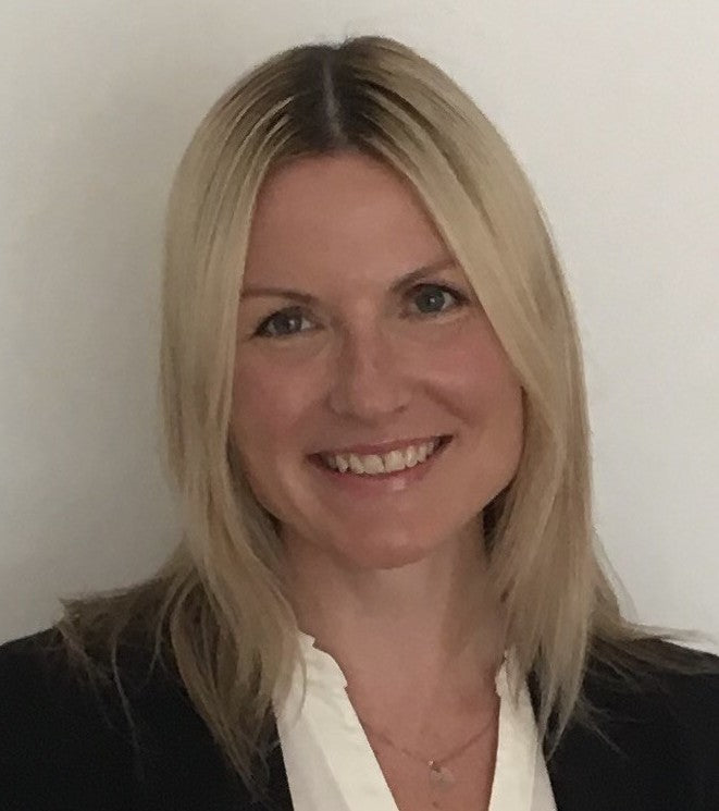 Kerry, a woman with straight blonde hair wearing a white collared shirt and black blazer against a plain background.