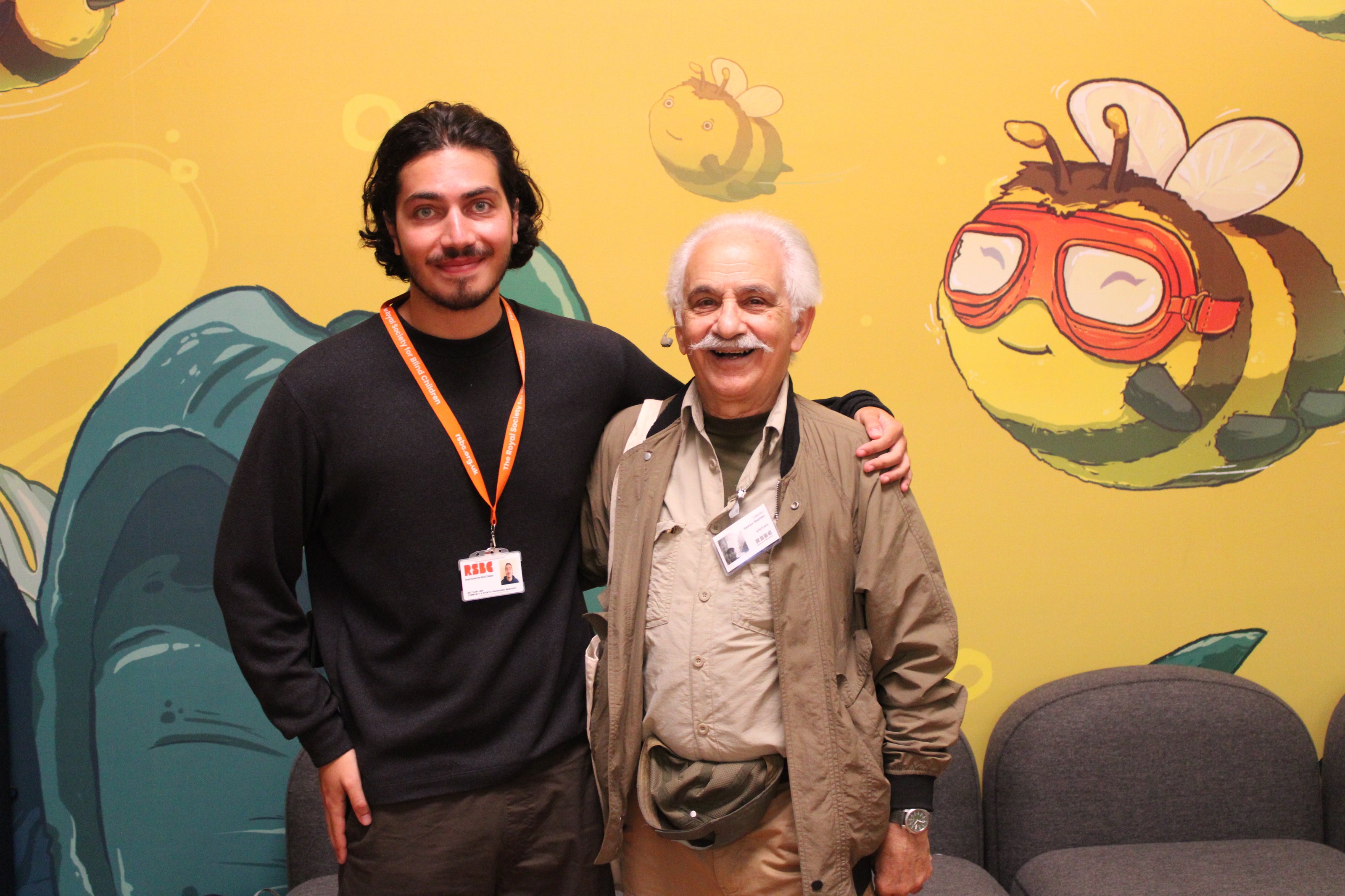 Matthew, RSBC's Community and Events Fundraising Manager standing with his arm around Sarkies. They're standing in RSBC's Life Without Limits main entrance smiling brightly at the camera. 