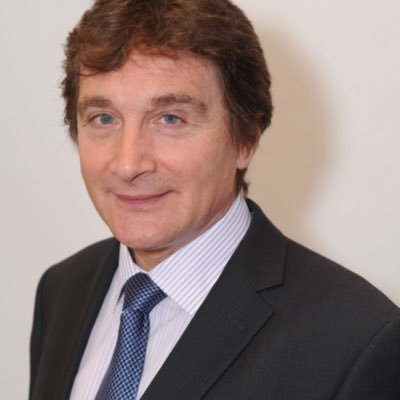 Our President, Dr Tom Pey, smiling at the camera in a smart blue suit