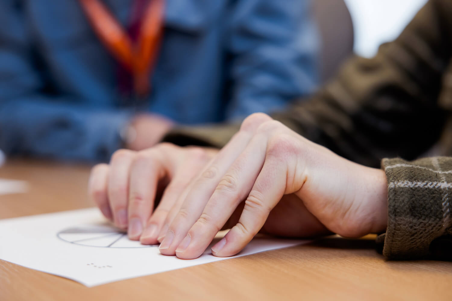 A close up of a young person's hands as they are learning braille