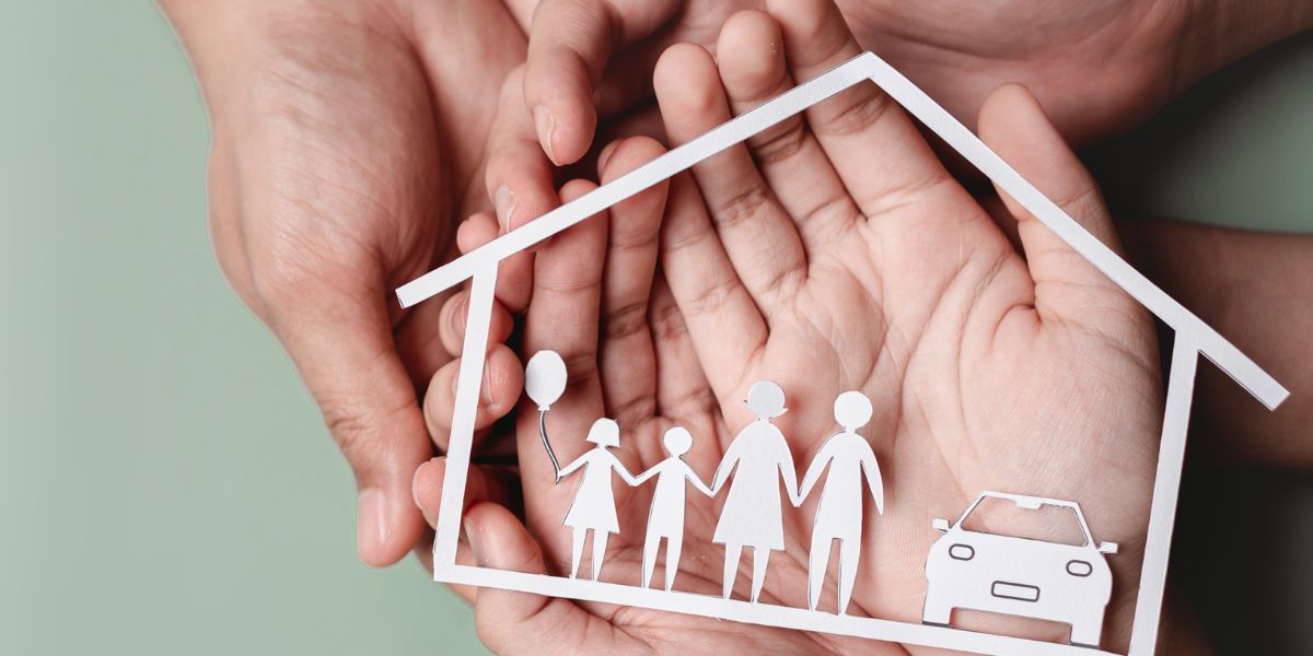 Different hands holding a cardbboard house with a family inside it.