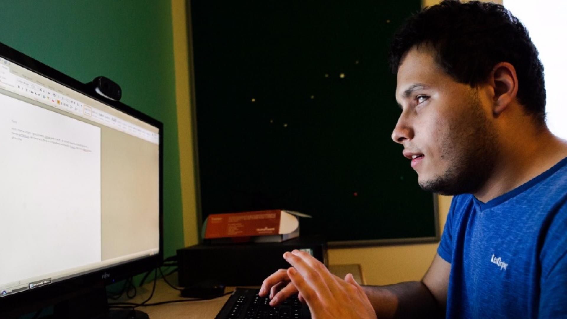 A blind young man studying in front of a computer