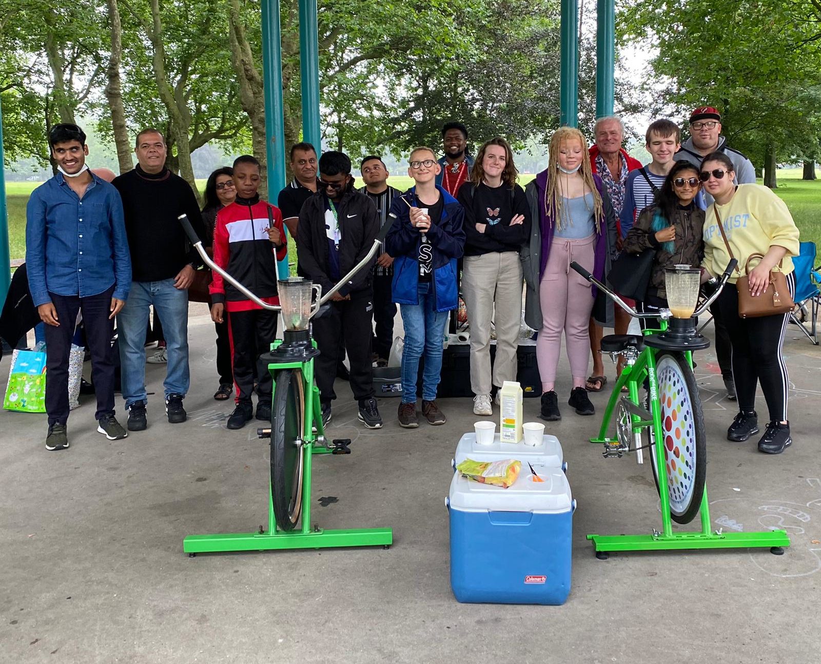 Group of young people standing together at Victoria park with two pedal powered smoothie bikes in front of them.