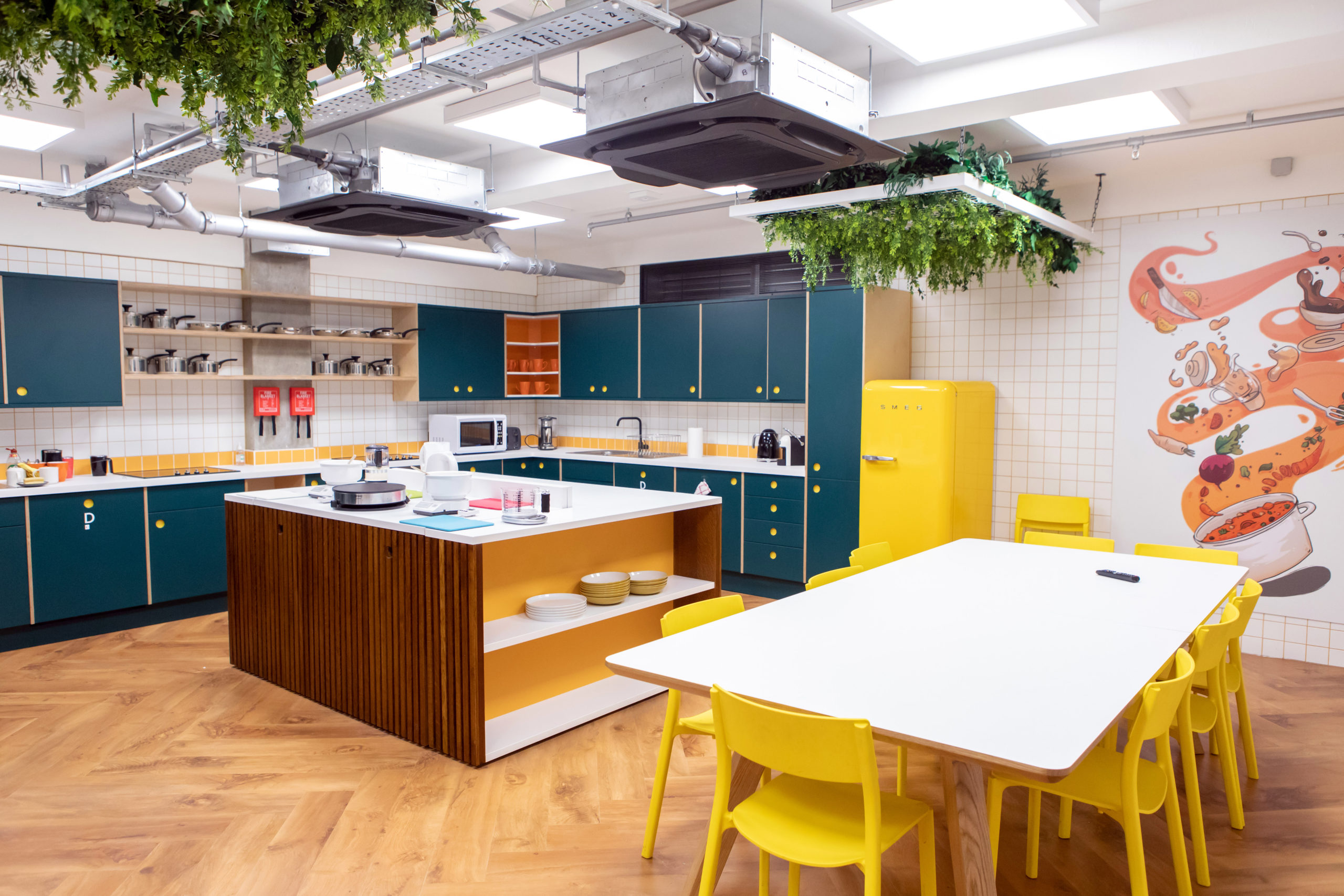 A large kitchen with square island, colour contrasting cabinets and a yellow table and chairs