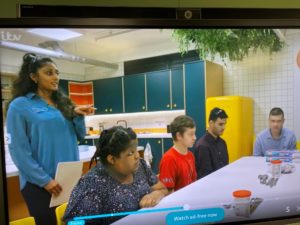 Children sit in front of table in kitchen. 