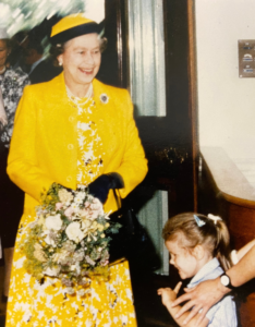 Her Majesty Queen Elisabet holding flowers with a girl next to her
