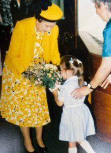 Her Majesty Queen Elisabeth offering flowers to a girl