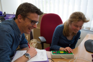 Two people smiling while doing an activity behind a desk