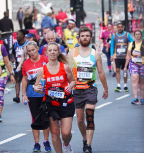 A woman running with the RSBC T-shirt in the middle of other runners at 2022 London Marathon
