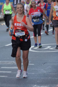 A woman running in front of other runners wearing RSBC T-shirt