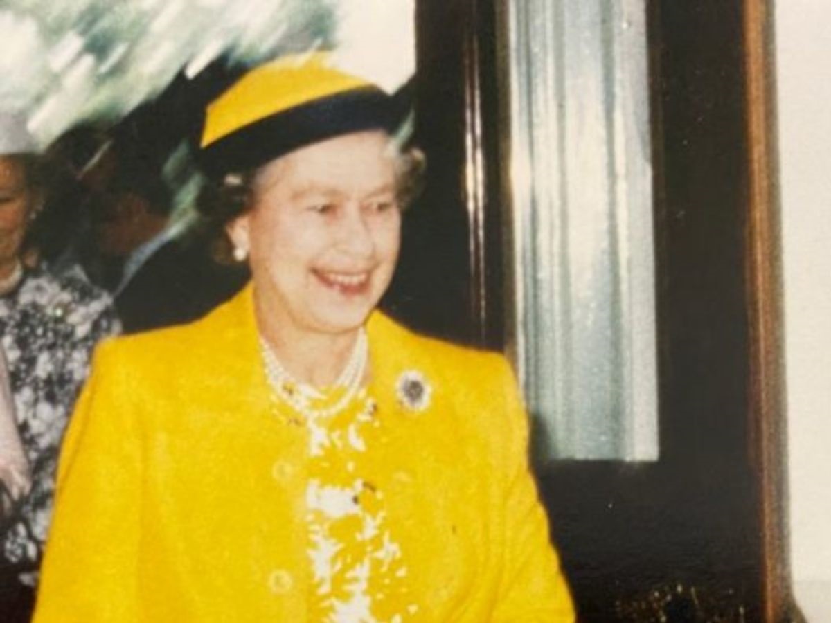 Her Majesty The Quuen Elizabeth 2 smiling in a yellow outfit