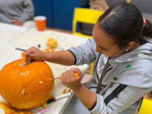 A young woman carving a pumpkin