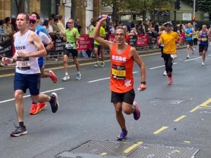 A man looking happy with his arm up running at the London Marathon