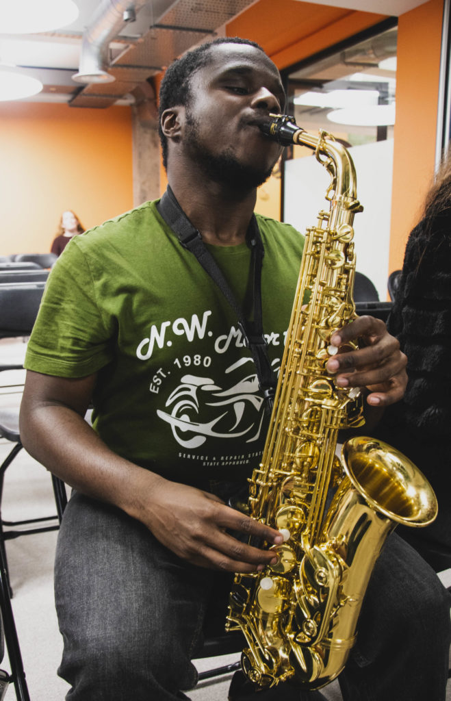 A young man seating and playing saxophone