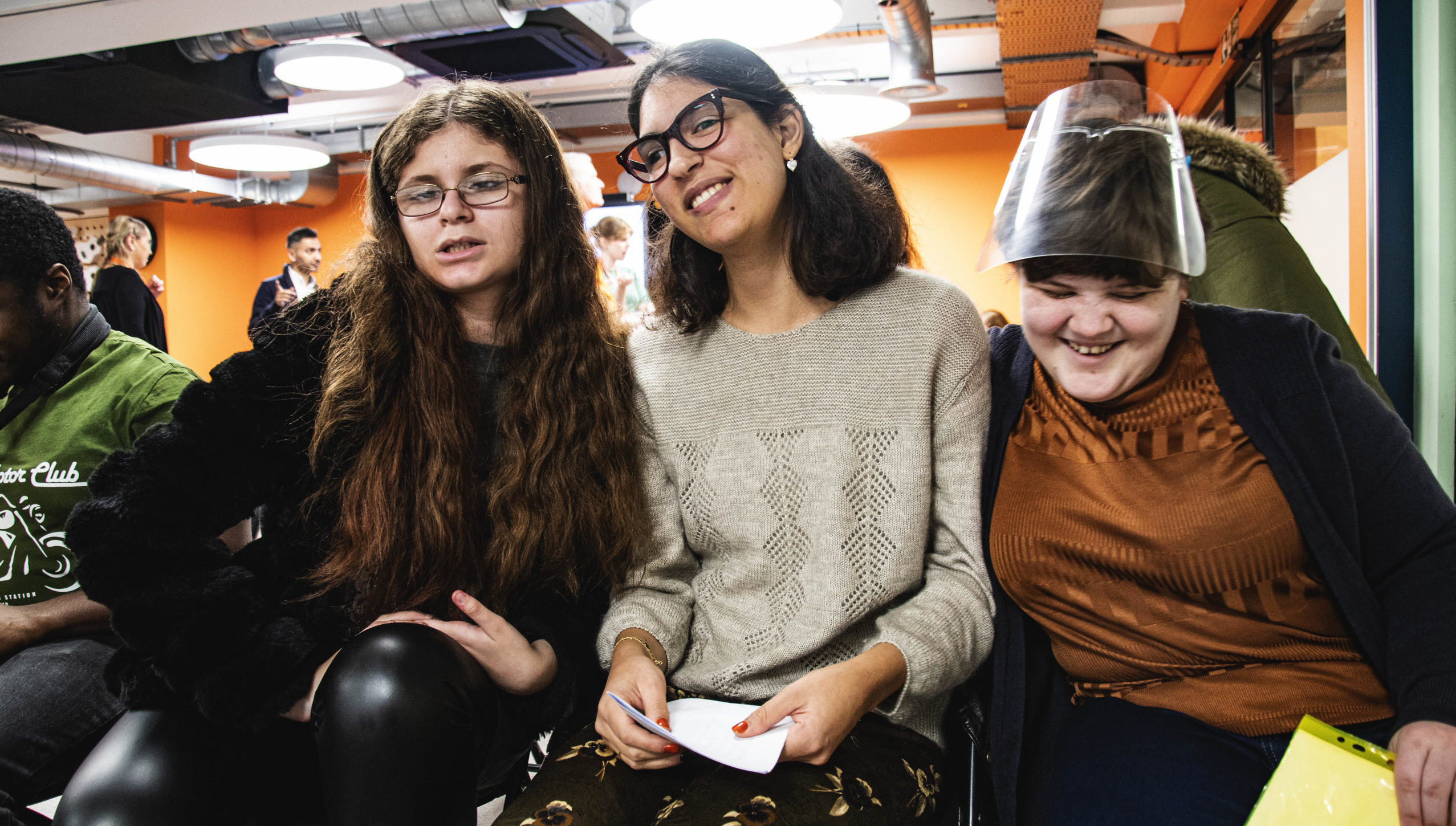 3 young women sitting next to each other and smiling