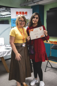 A young woman receiving a certificate standing up next a woman