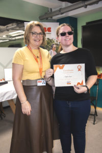 A young woman receiving a certificate standing up next a woman