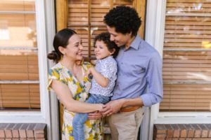 A mother and father holding their child smiling