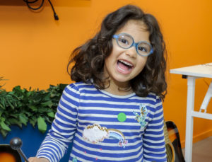 A young girl smiling behind a xylophone