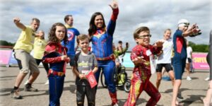 A group of adults and childrens dressed up in superhero costumes
