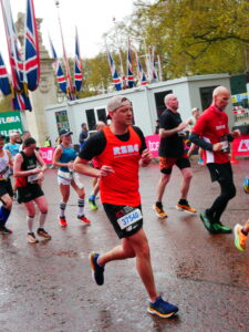 A man with RSBC orange vest running at the London Marathon finish line