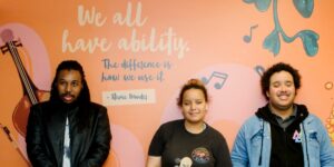 3 young people standing up against a colourful wall with a quote that reads: "We all have ability the difference is how we use it. Steve Wonder"