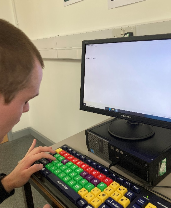 A young men typing on a colourful keyboard