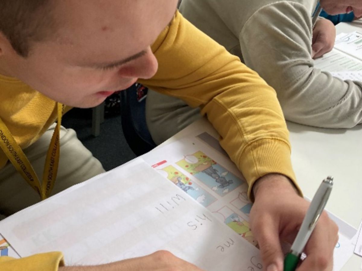 A young man studyng at his desk holding a pen.