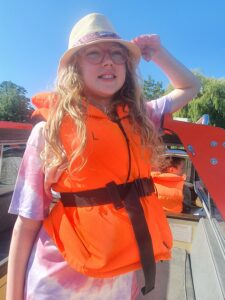 A young girl wearing a hat and an orange float vest